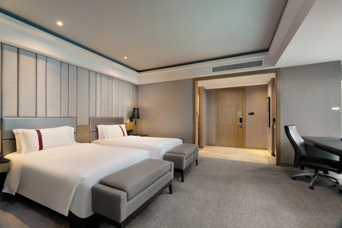 Une chambre d’hôtel avec deux lits, un bureau et une chaise.