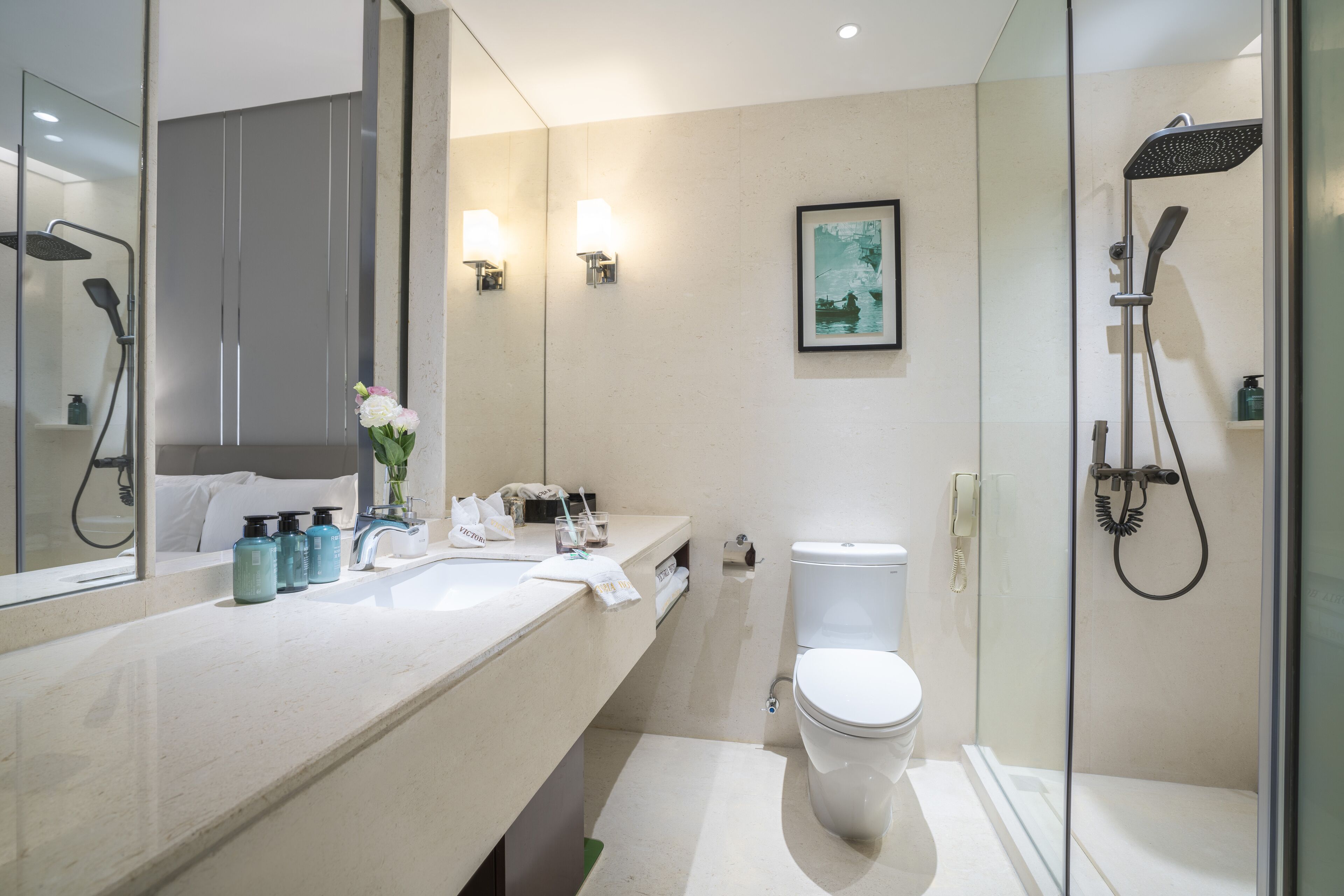 Une salle de bain moderne avec un grand miroir, des toilettes, une douche et un lavabo équipé de produits de toilette.