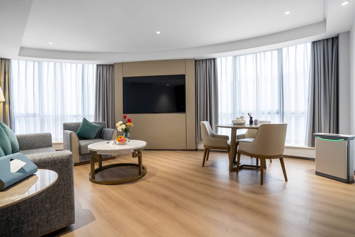 Una habitación de hotel moderna con zona de estar, una mesa de comedor y un televisor de pantalla plana.
