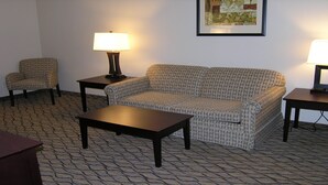 Ein Wohnzimmer mit einem gemusterten Sofa, zwei Sesseln, einem Couchtisch und zwei Beistelltischen mit Lampen.
