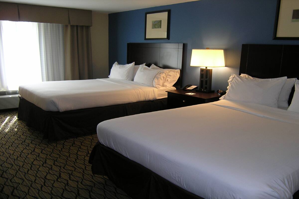 A hotel room with two beds, a nightstand with a lamp, and a framed picture on the wall.