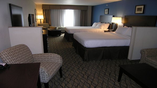 A hotel room with two beds, a desk, a chair, a TV, and a window with curtains.