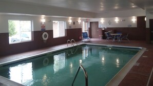 Ein Hallenbad mit Rettungsboje, Liegestühlen und einem kleinen Tisch.