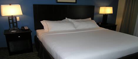 A hotel room with a large bed, two bedside tables with lamps, and a framed picture on the wall.