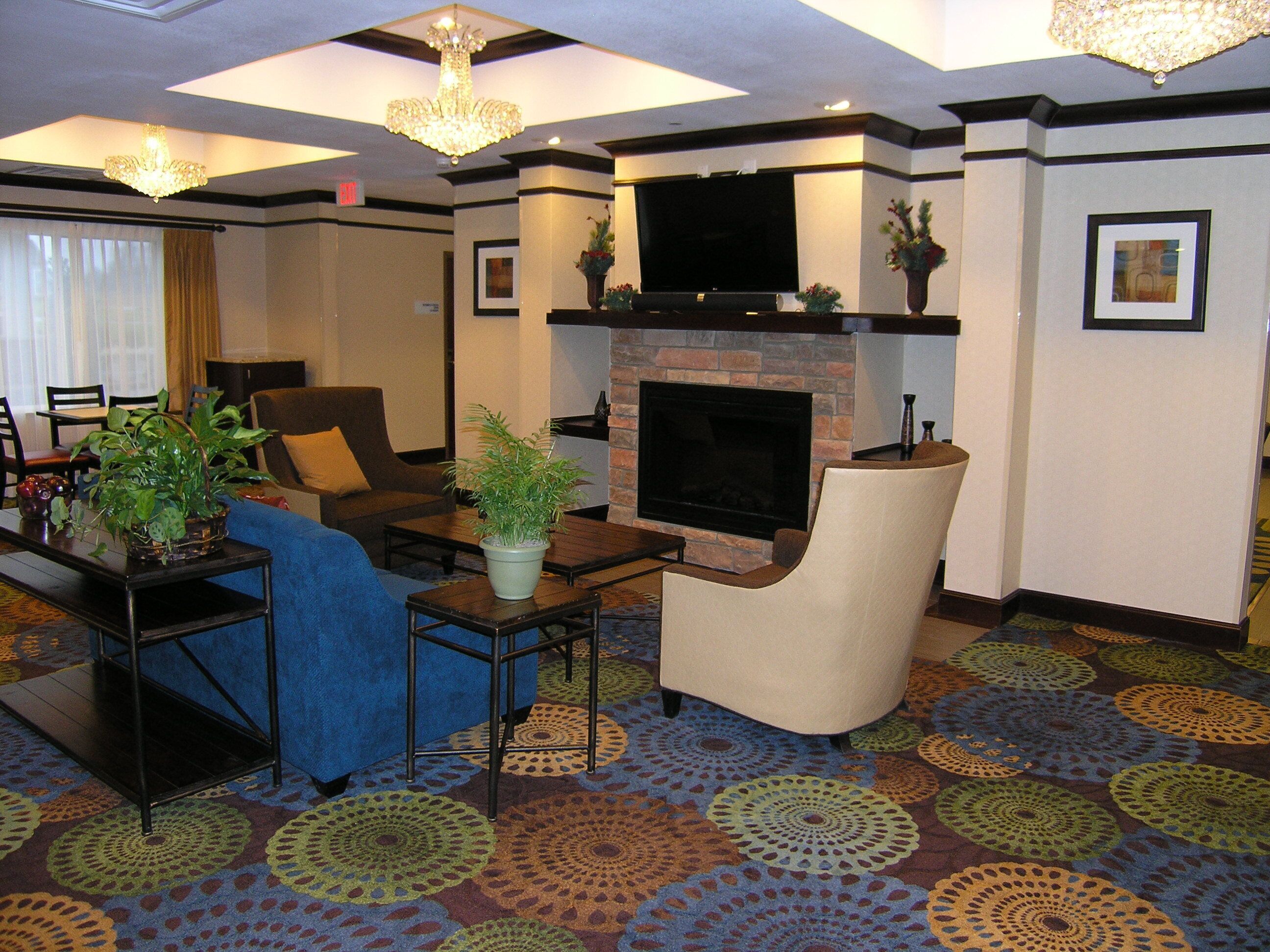 A hotel lobby with a fireplace, seating area, and a television.