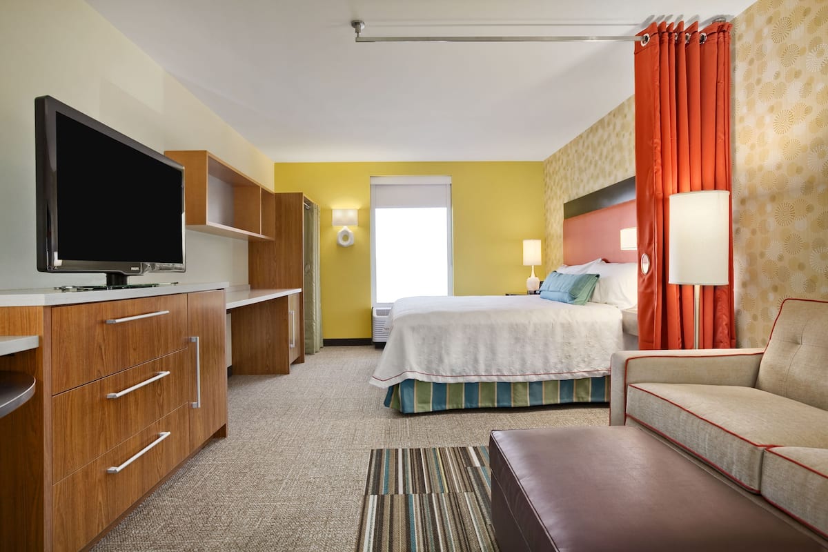 Een hotelkamer met televisie, bed, bank, bureau en badkamer.