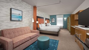 Een hotelkamer met een bed, een slaapbank, een televisie en een bureau.
