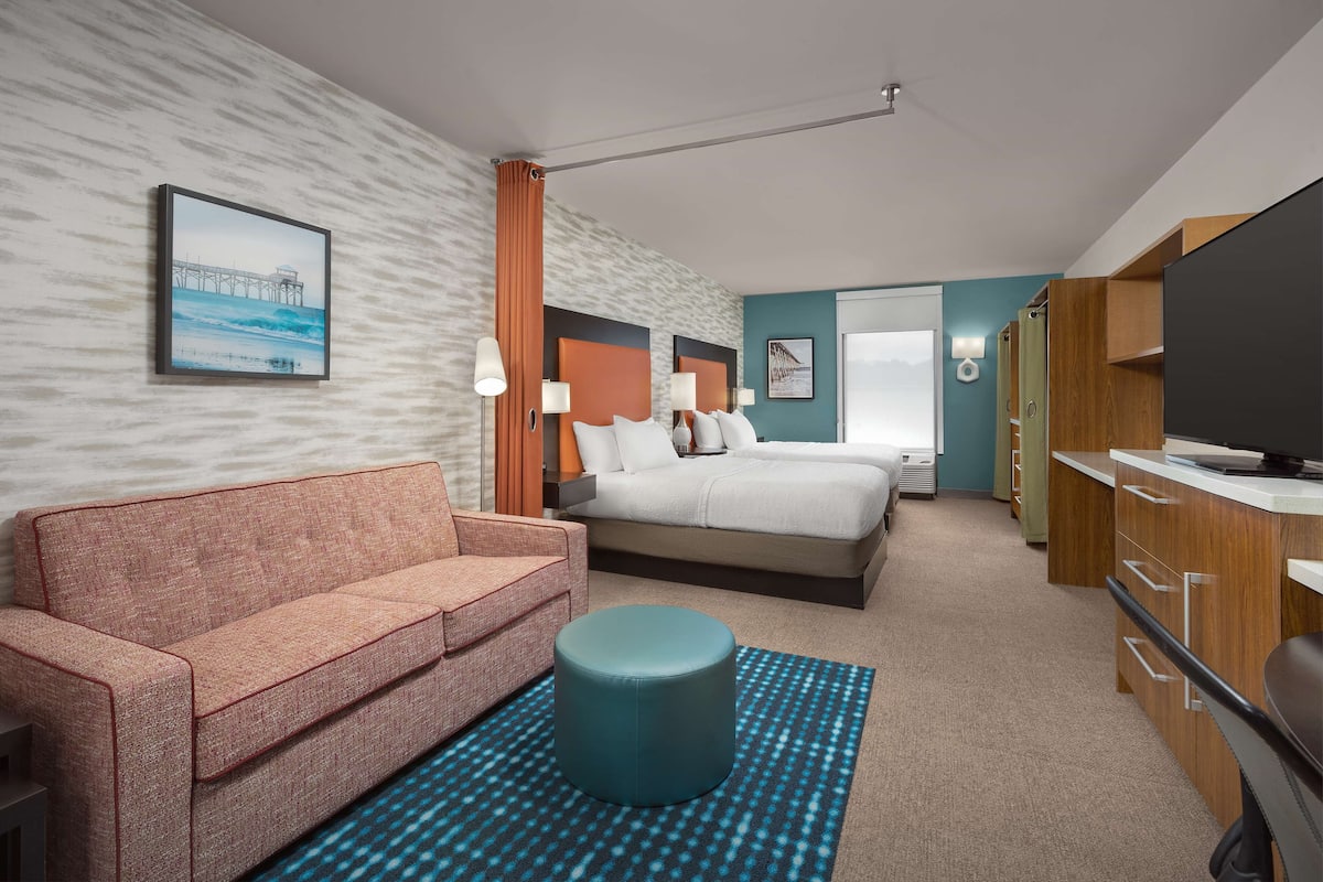 Een hotelkamer met een bed, een slaapbank, een televisie en een bureau.