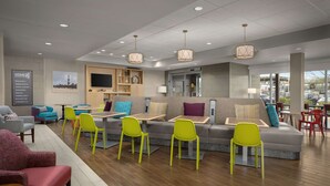 Een moderne hotellobby met een zithoek, een televisie en een receptiebalie.