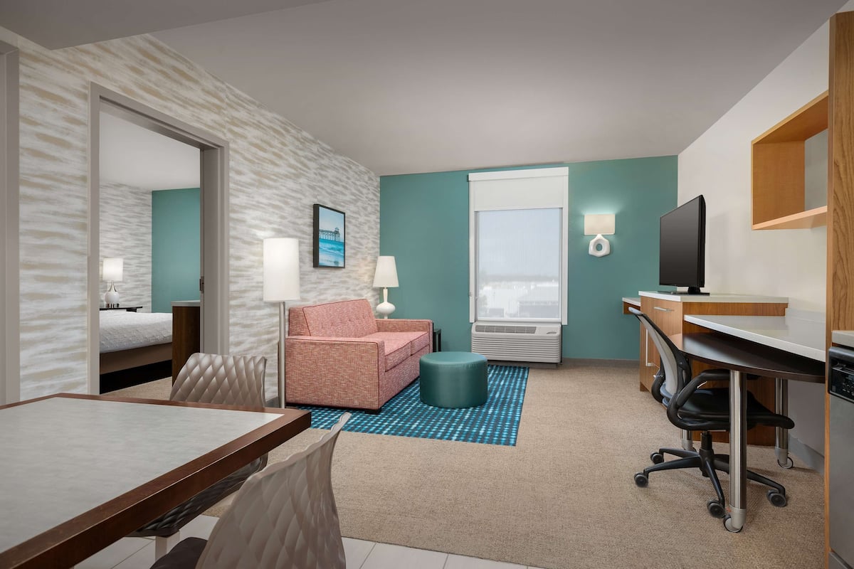 Een hotelkamer met een bed, een bureau, een stoel, een bank, een televisie en een raam.