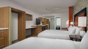 A hotel room with two beds, a desk, a television, and a bathroom visible through an open door.