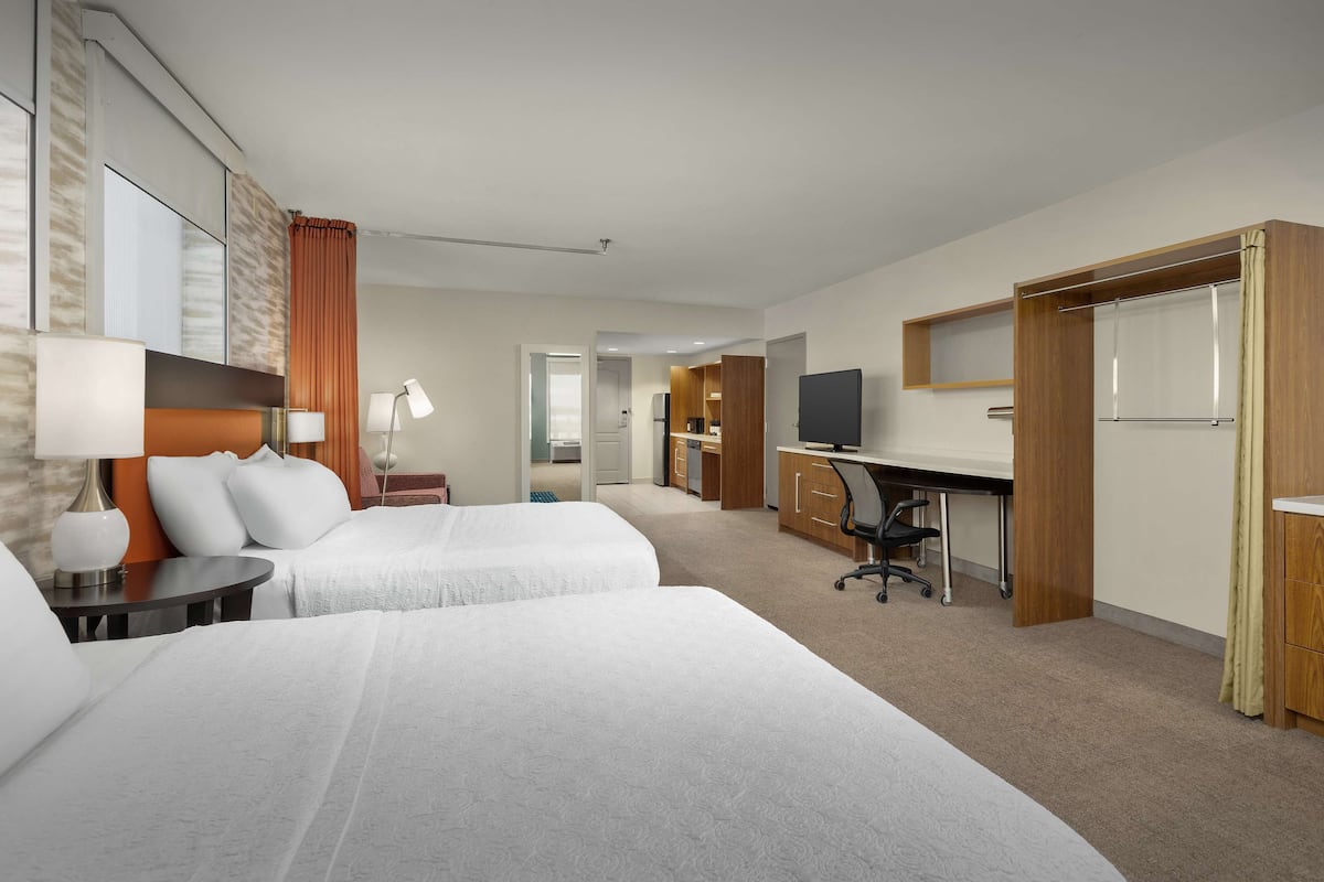 Een hotelkamer met twee bedden, een bureau, een televisie en een kledingkast.