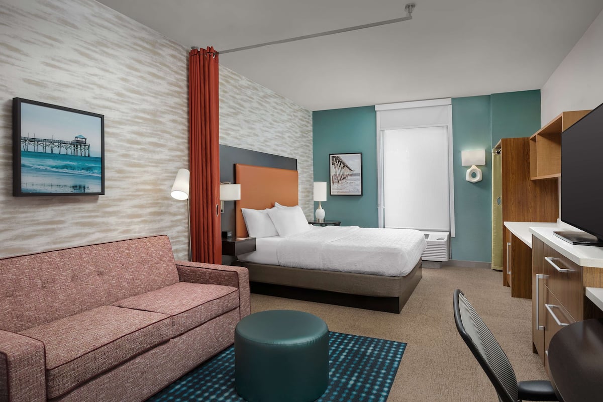 Een hotelkamer met een bed, een slaapbank, een bureau en een televisie.