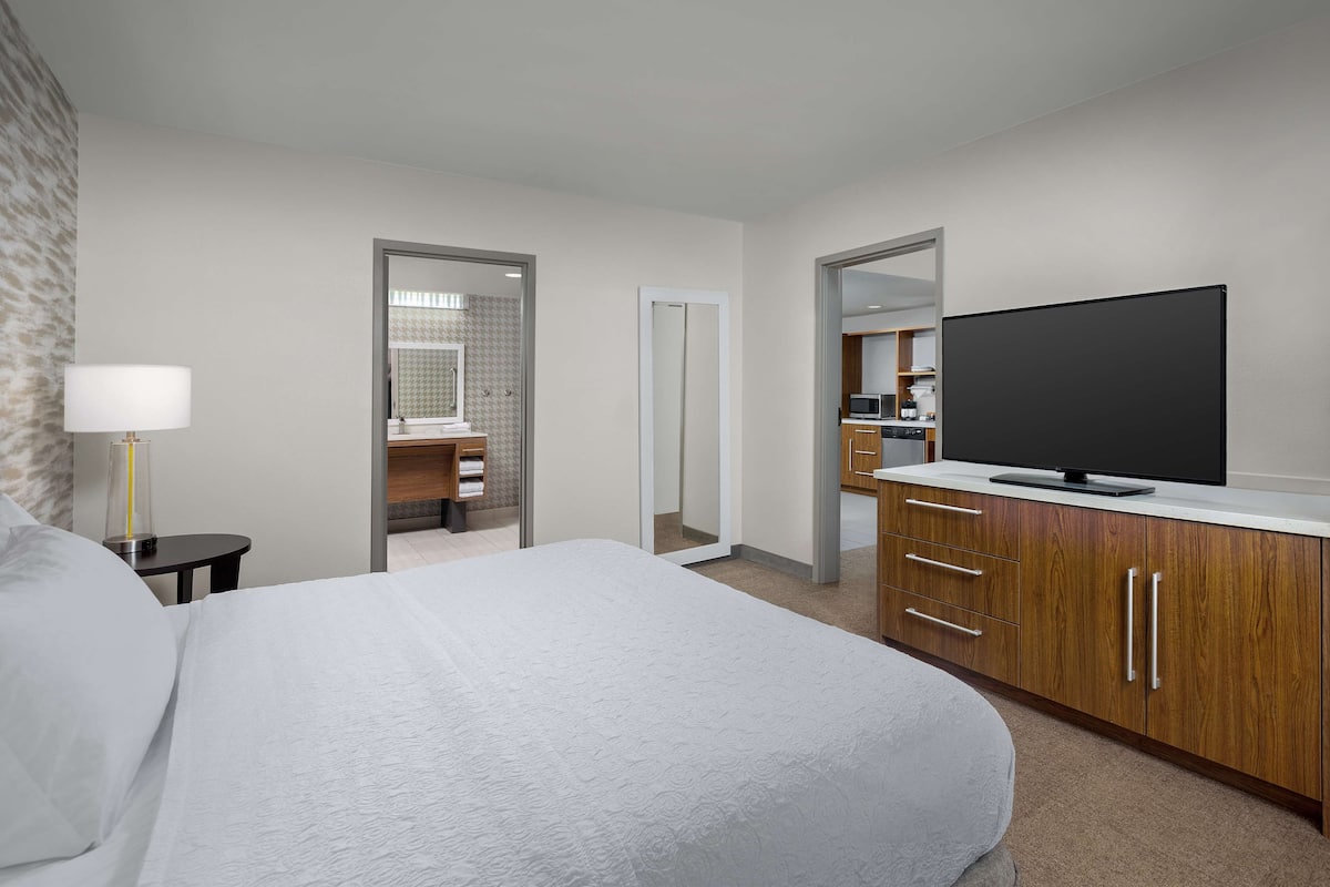 Hotelkamer met een groot bed, een televisie, een bureau en een badkamer door een geopende deur.