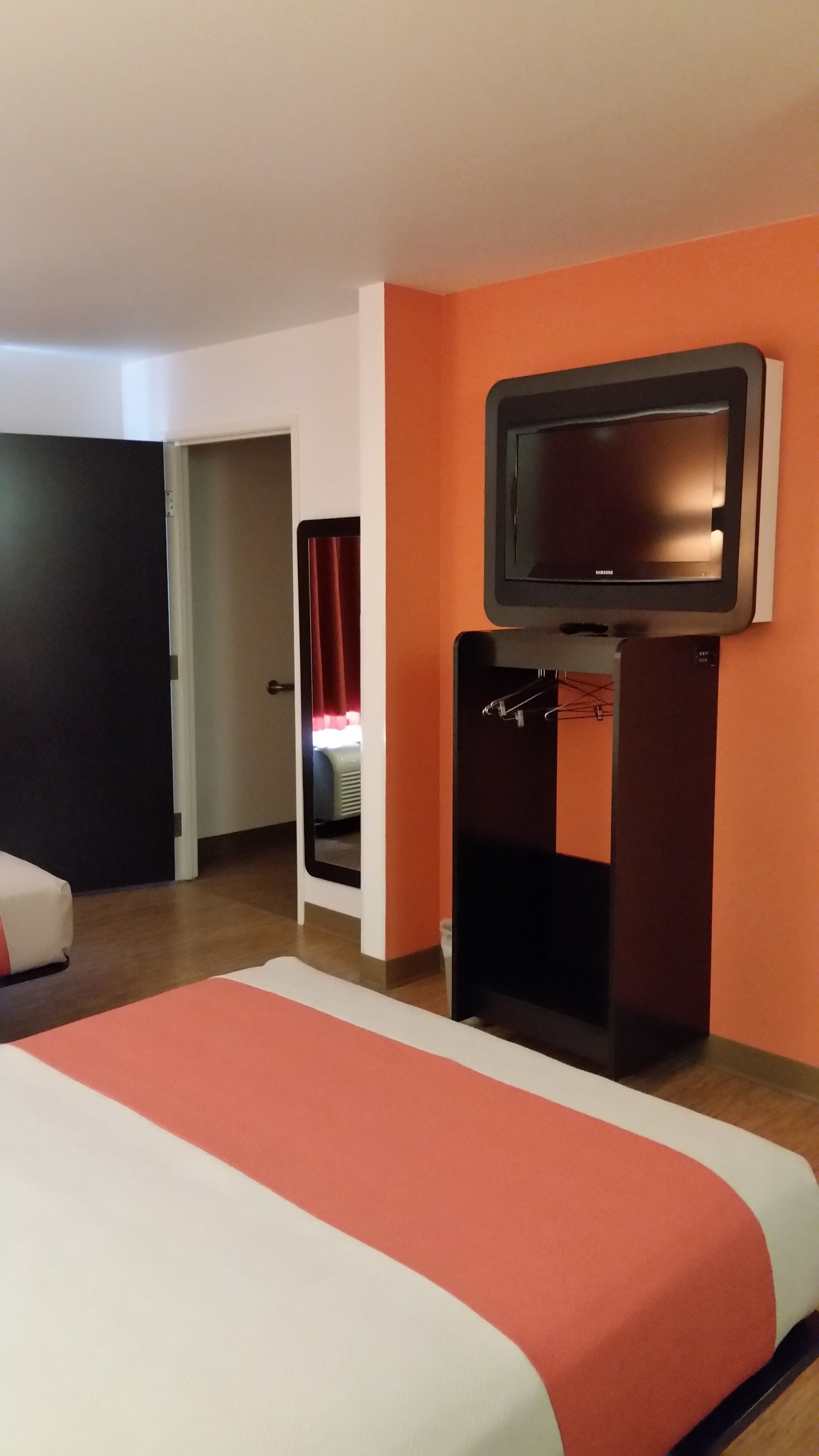 Habitación de hotel con una cama, un televisor y una puerta que da a un baño.