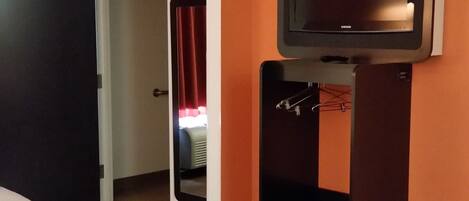 Habitación de hotel con una cama, un televisor y una puerta que da a un baño.