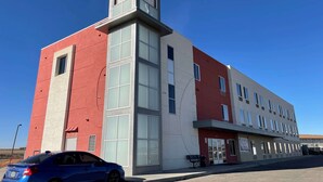 A modern building with a red and white facade, large windows, and a visible entrance.