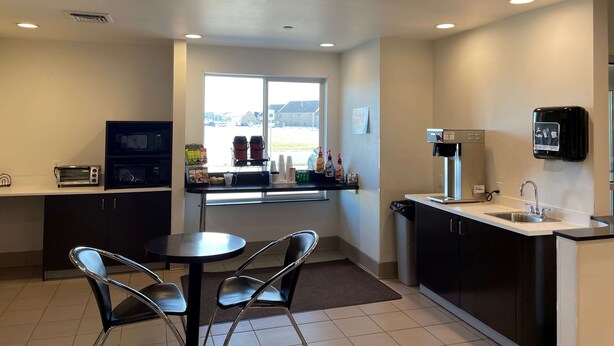 A compact kitchen area with a microwave, toaster, and coffee machine. There is a window providing a view of the outside, and a sink with a soap dispenser.