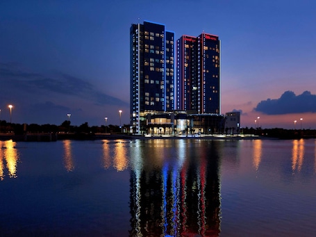 A high-rise hotel with multiple floors, a waterfront view, and illuminated windows.