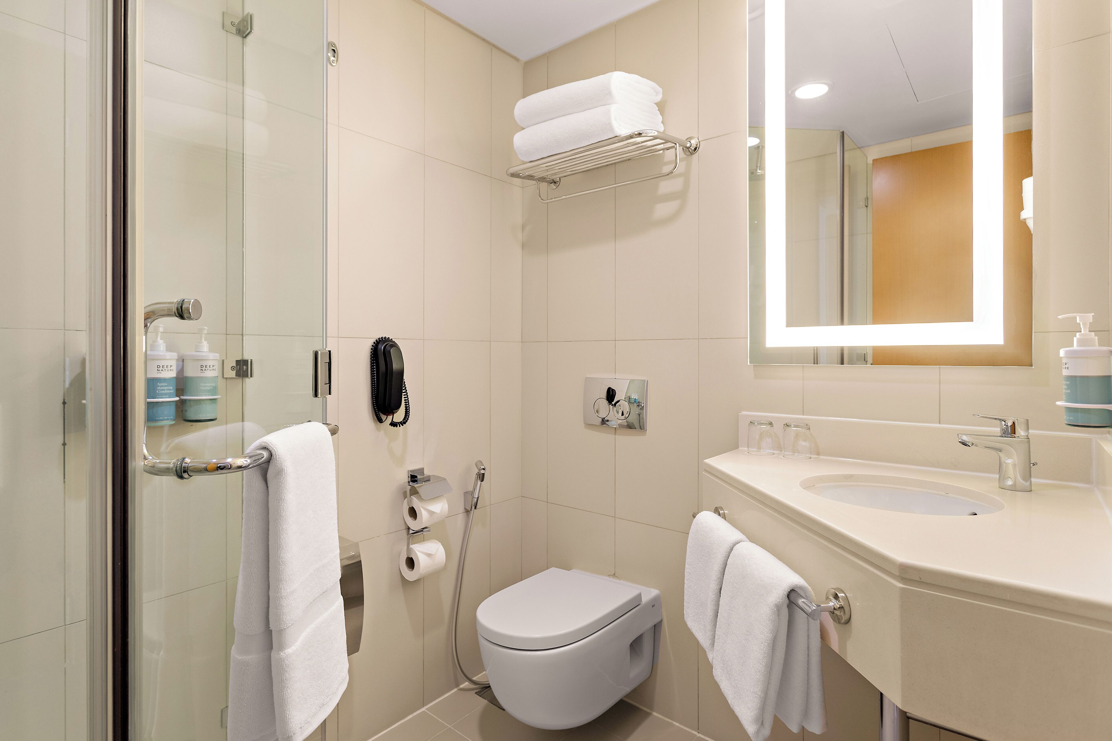 Ein modernes Badezimmer mit Duschkabine aus Glas, Toilette, Waschbecken mit Spiegel und Handtuchhalter.