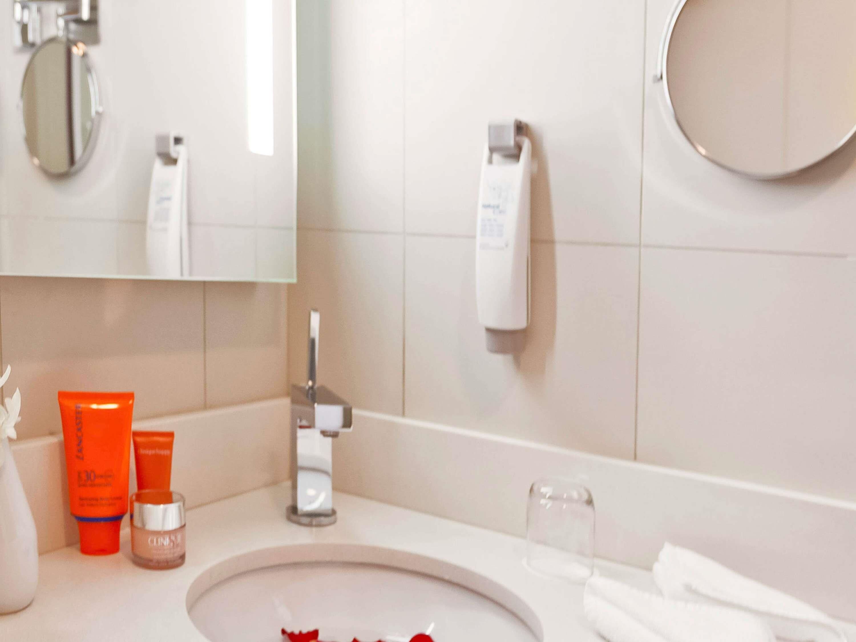 A bathroom with a sink, mirror, and toiletries.