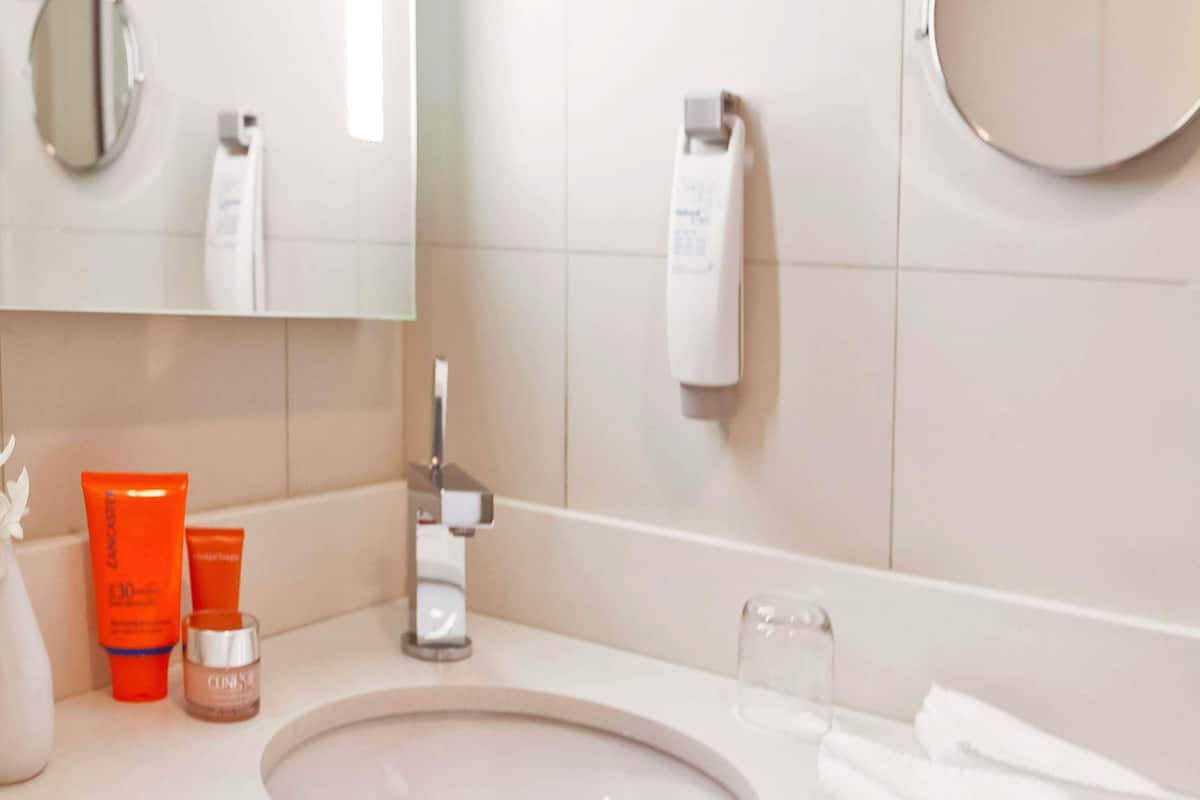A bathroom with a sink, mirror, and toiletries.