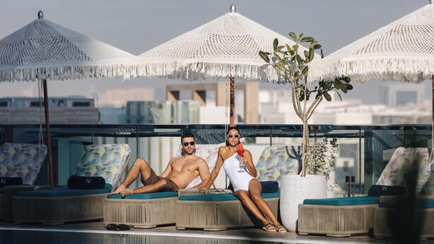 A rooftop pool area with lounge chairs, umbrellas, and a potted plant. - ibis Abu Dhabi Gate (Abu Dhabi)