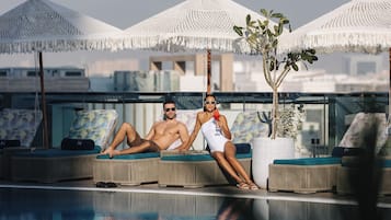Una piscina al aire libre, sombrillas, tumbonas