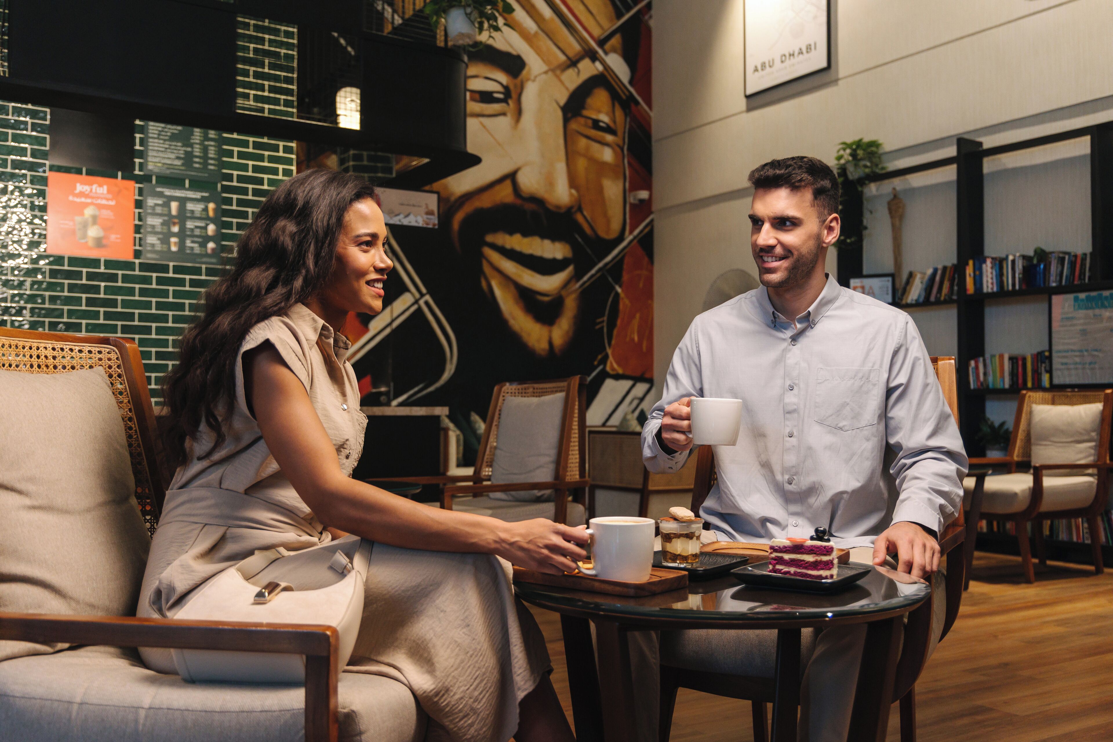 A cafe setting with a mural, seating, and a table with a cake and drinks.