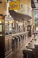 Interior de un café belga con taburetes de madera, una barra y lámparas colgantes.
