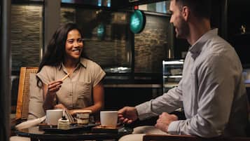 A cafe setting with a table, chairs, and a coffee machine.