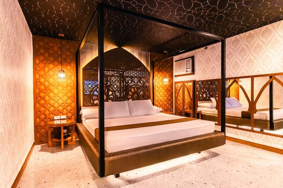 A room with a bed, a small table, and a decorative wall.