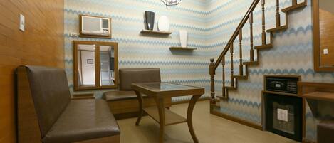 A room with a wooden bench, a table, a staircase, and a patterned wall.