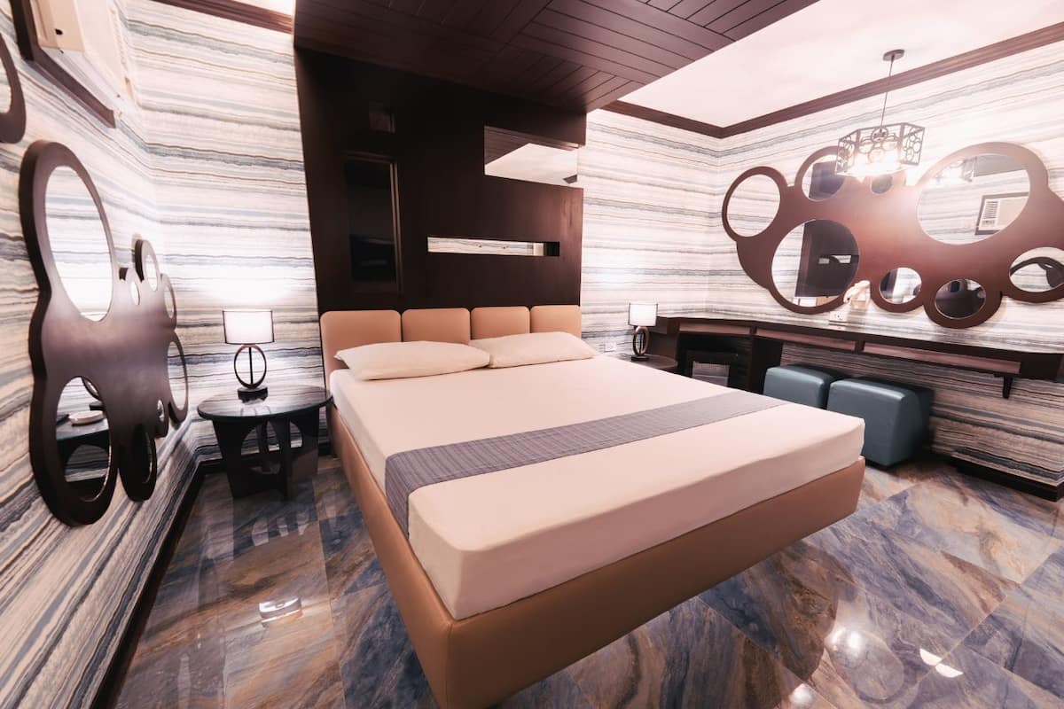 A modern bedroom with a large bed, a small table, and a unique wall design.