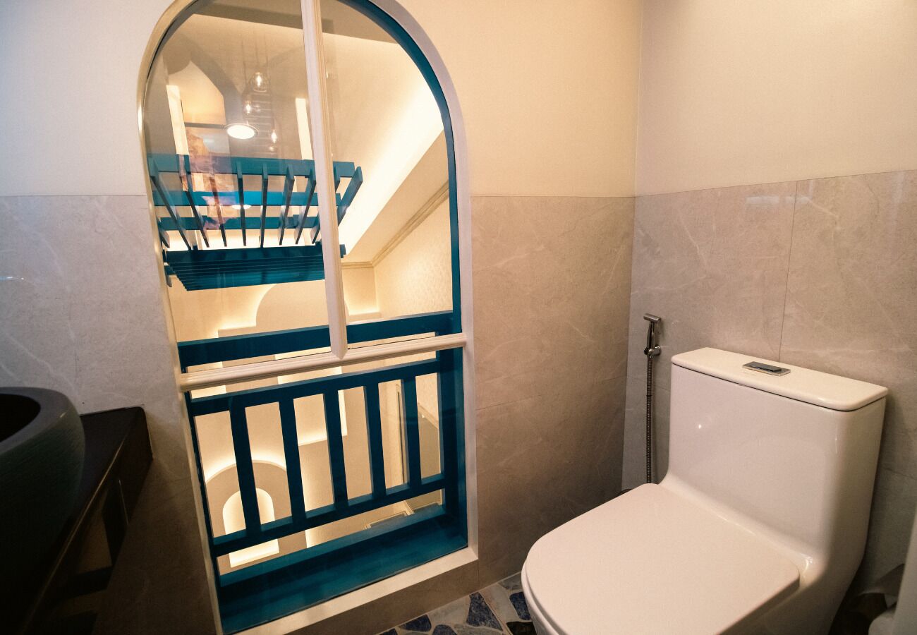A bathroom with a toilet, a shower, and a glass-enclosed staircase.