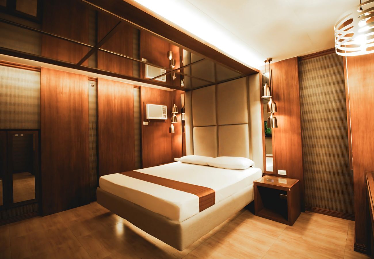 A modern bedroom with a large bed, wooden paneling, and built-in lighting.