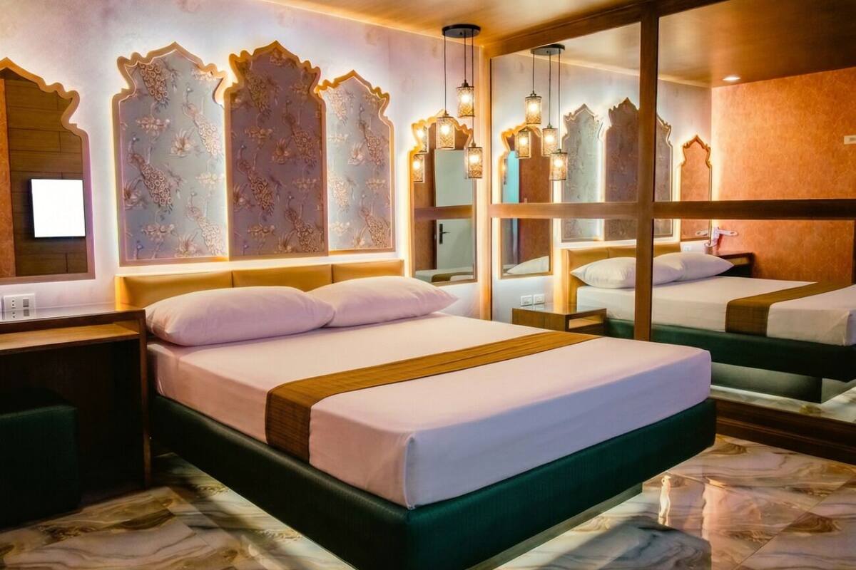 A hotel room with a large bed, bedside tables, a mirror, and a patterned floor.