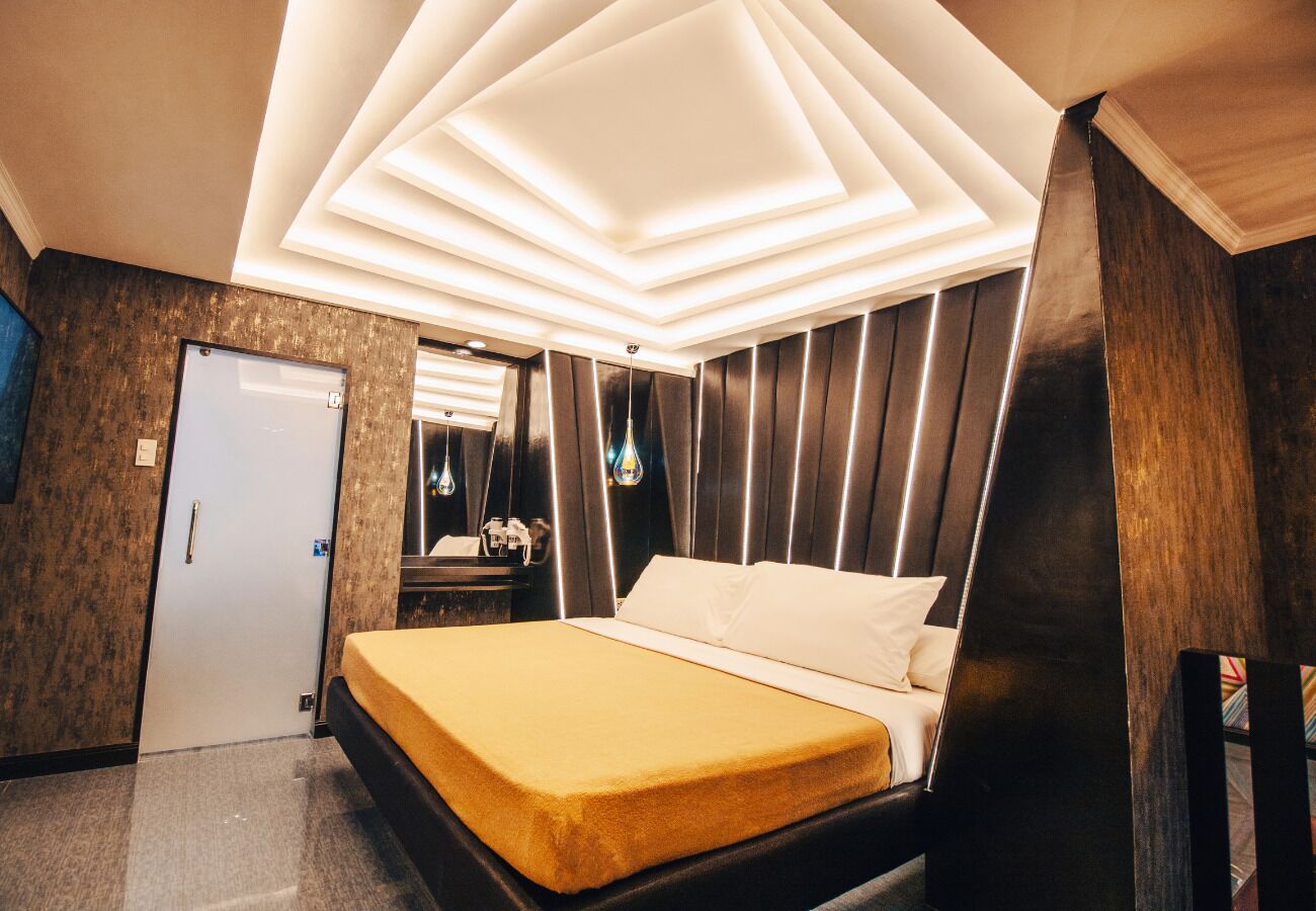 A modern hotel room with a bed, a wardrobe, a mirror, and a door.