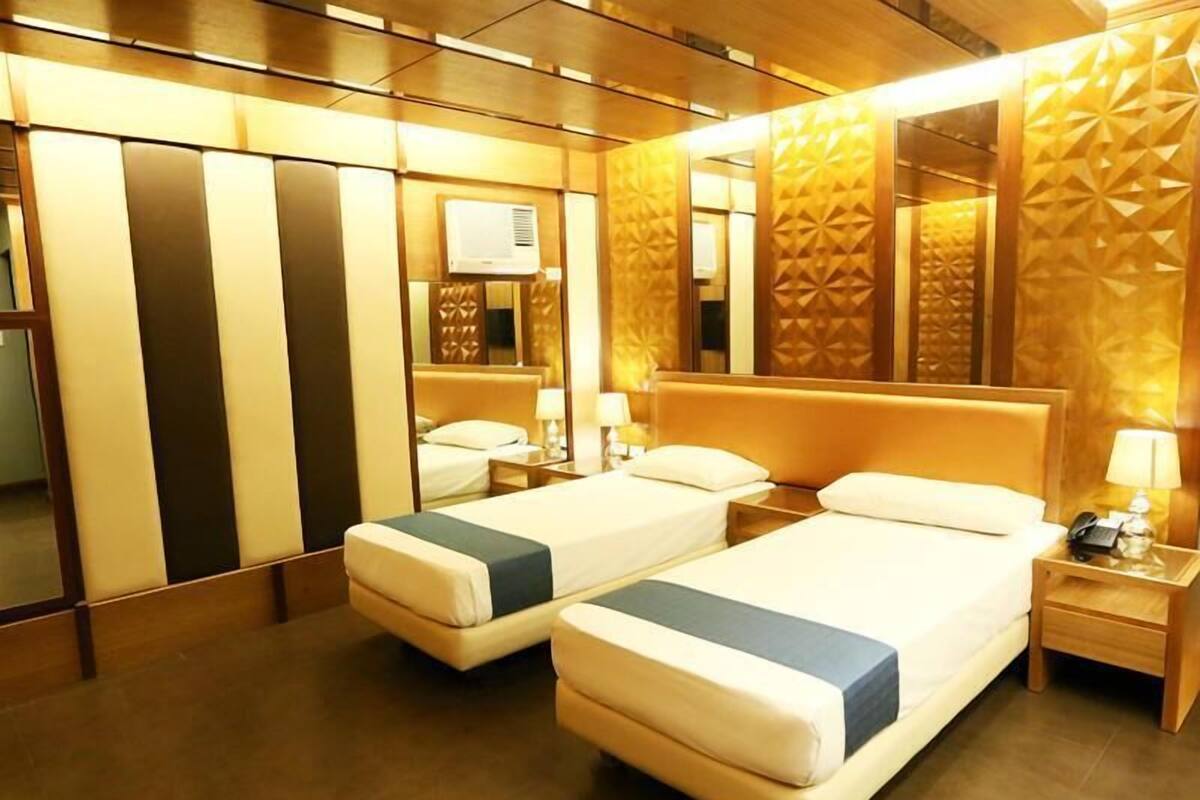 A hotel room with two beds, a large mirror, and a wall-mounted air conditioner.