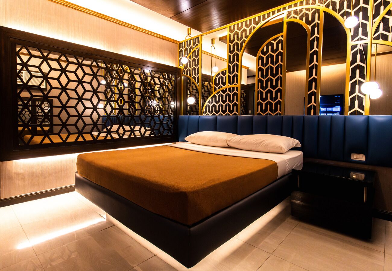 A modern bedroom with a bed, a nightstand, and a decorative wall panel.
