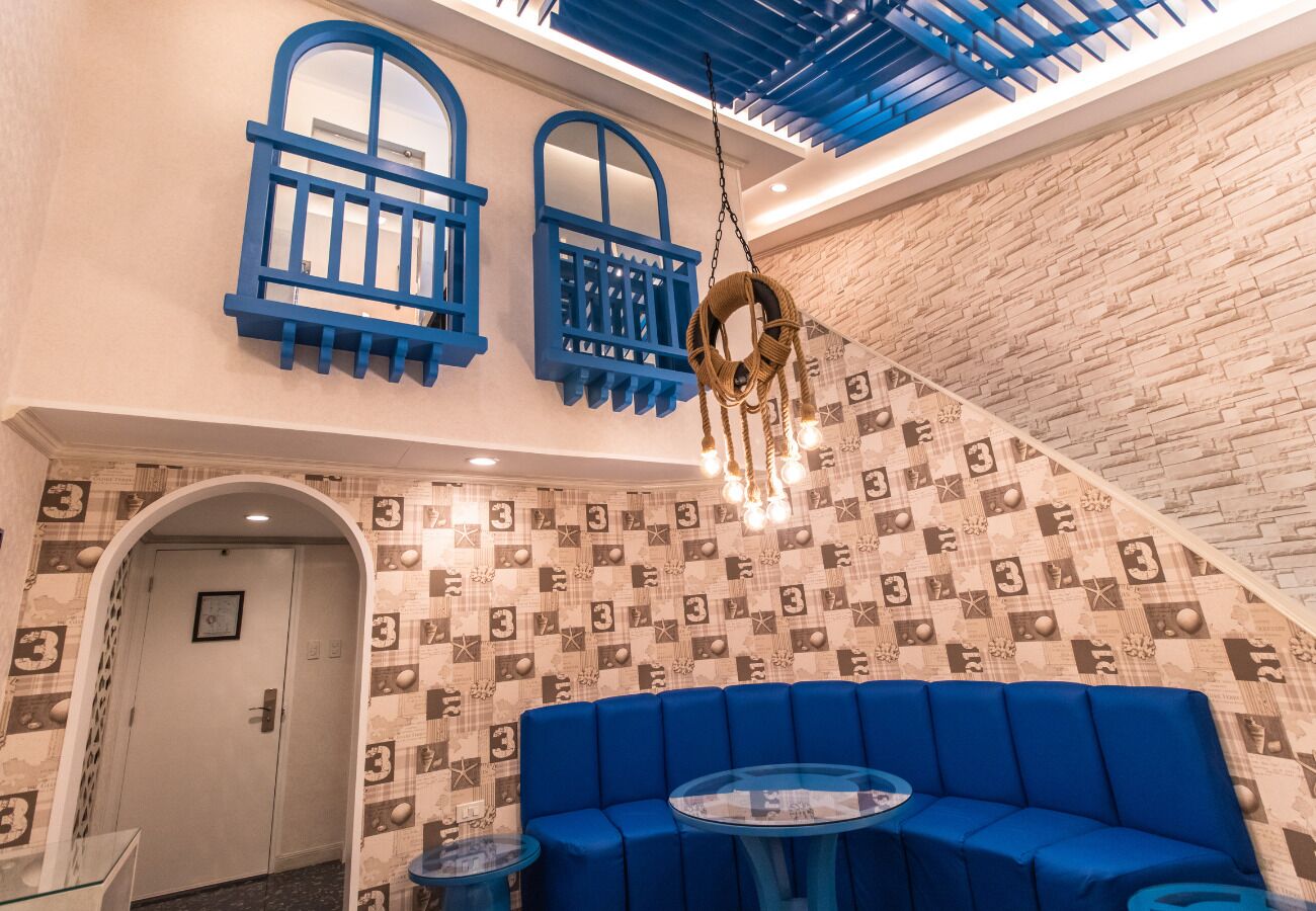 A blue sofa, a hanging chair, and a patterned wall.
