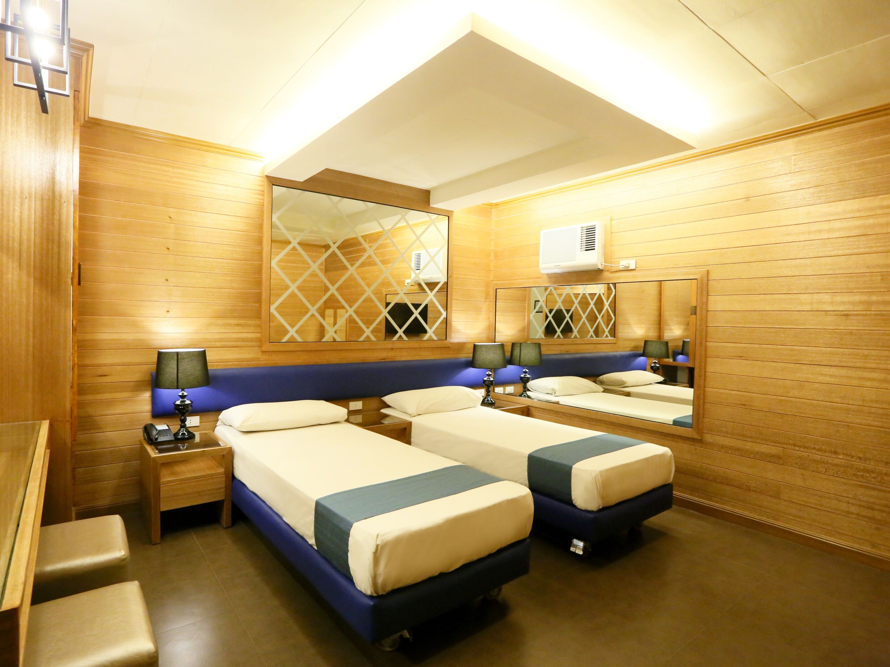 Une chambre d’hôtel avec deux lits simples, un bureau, une chaise et un miroir.