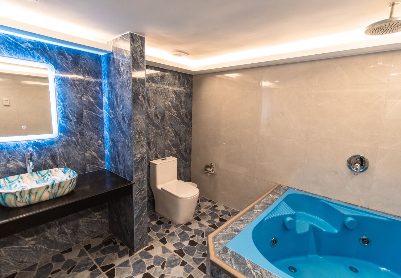 A bathroom with a marble sink, a toilet, and a blue jacuzzi tub.