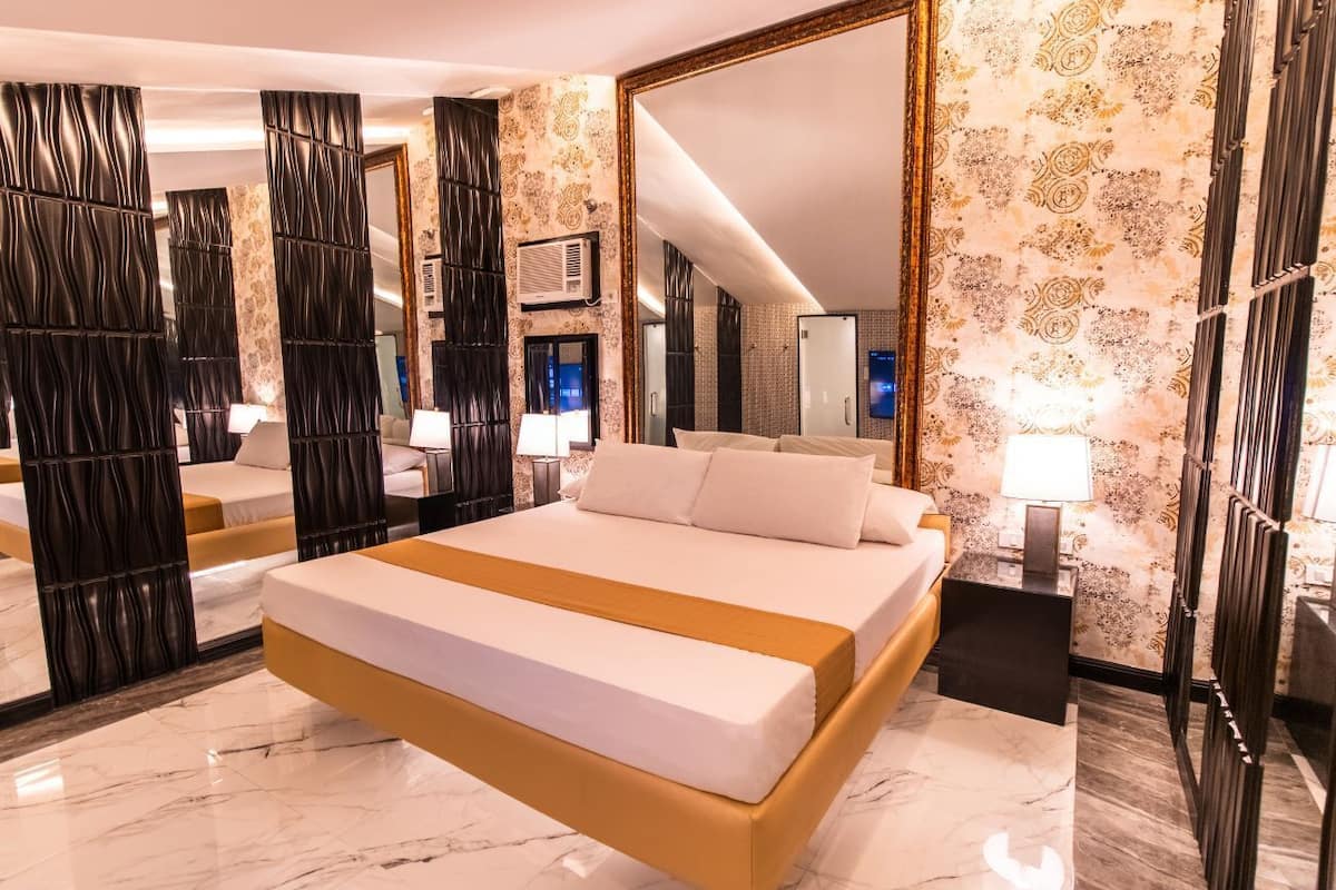 A modern hotel room with a large bed, a mirror, and a decorative wall.