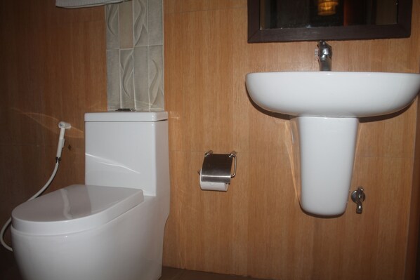 Un baño con inodoro, lavamanos y dispensador de papel higiénico.