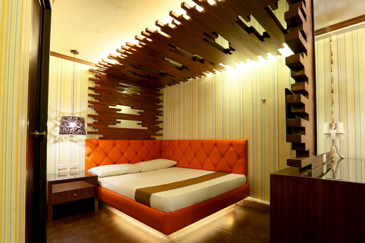 A modern bedroom with a tufted orange headboard, a bedside table, and a wall-mounted telephone.