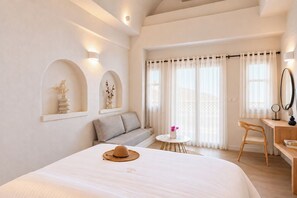 A hotel room with a bed, a sofa, a desk, and a small table.