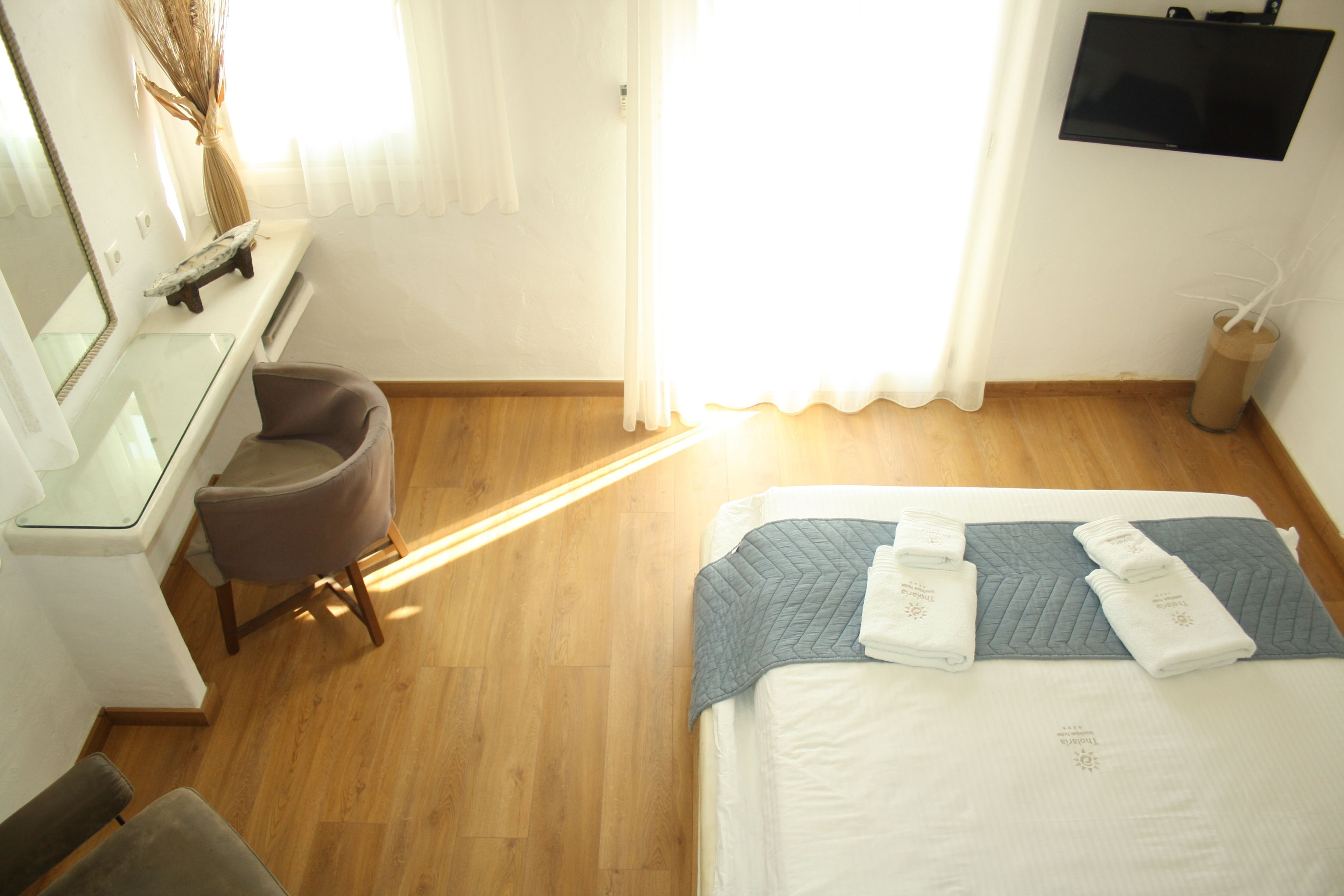 Una habitación de hotel con cama, escritorio, silla, espejo y televisor.