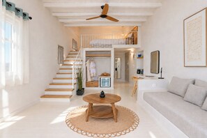 Un amplio salón con escaleras, una mesa de centro redonda de madera y un sofá.