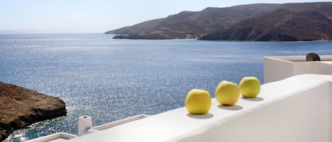 A coastal view with a clear sky, a body of water, and a white building with three yellow objects on its facade.